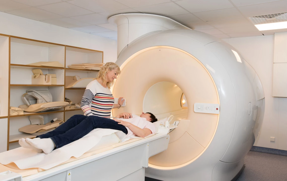 Eine Frau redet mit einer Patientin die auf einem Röntgengerät liegt.