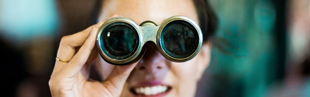 Frau blickt durch Fernglas