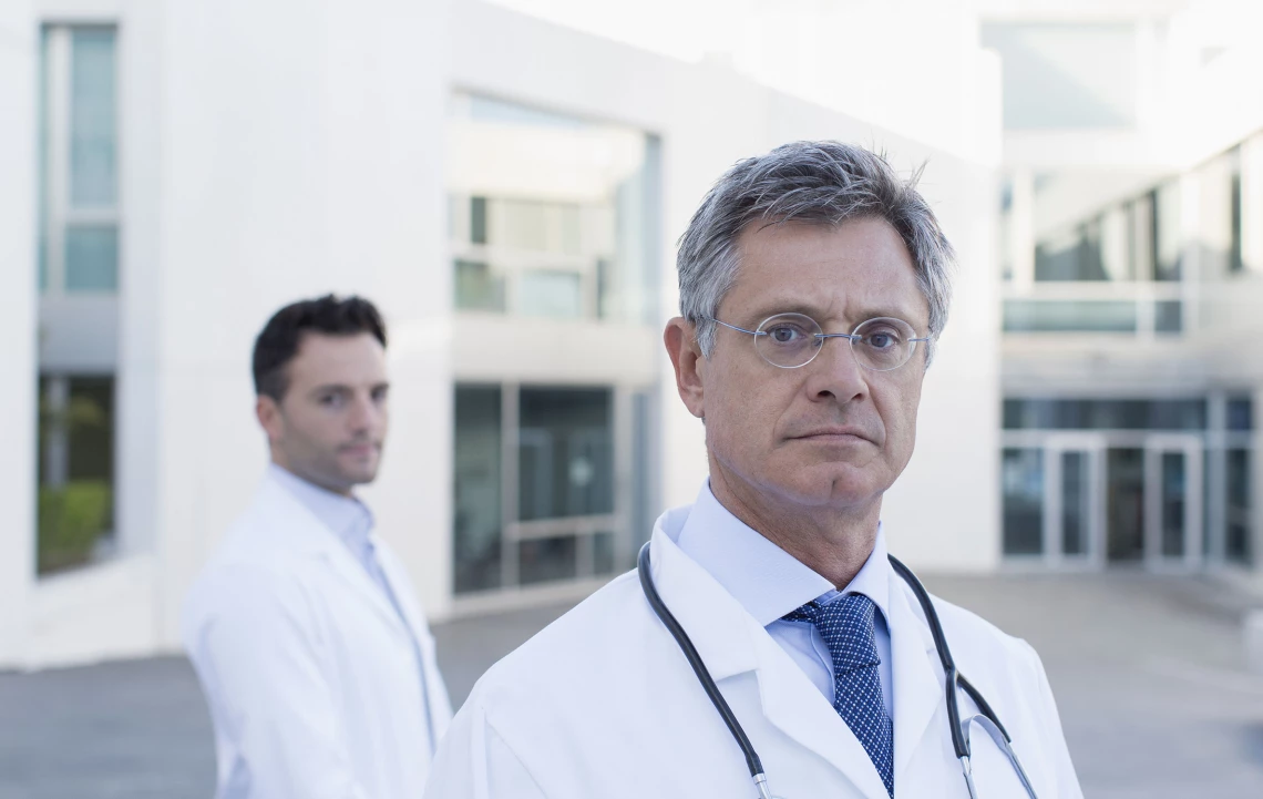Zwei Ärzte stehen vor einem Krankenahaus.
