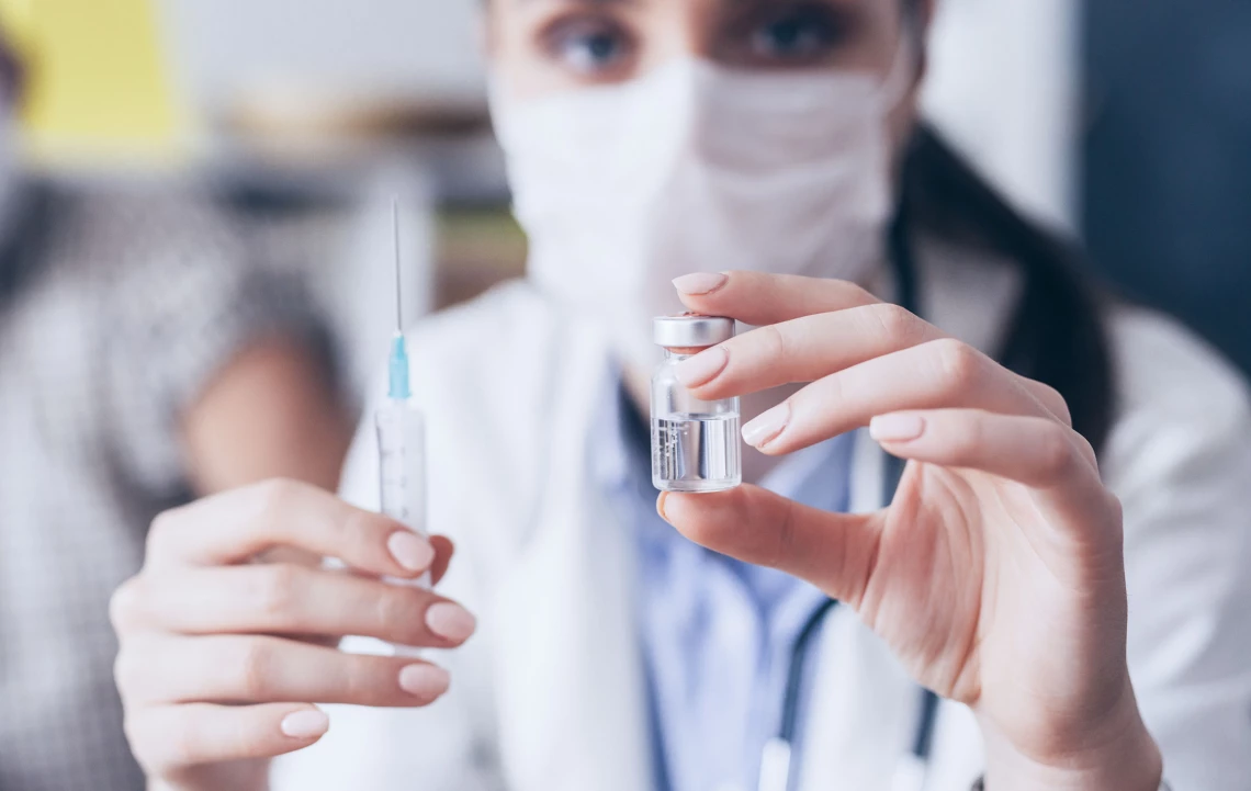 Eine Ärztin hält eine Spritze und Impfdosis in den Händen.