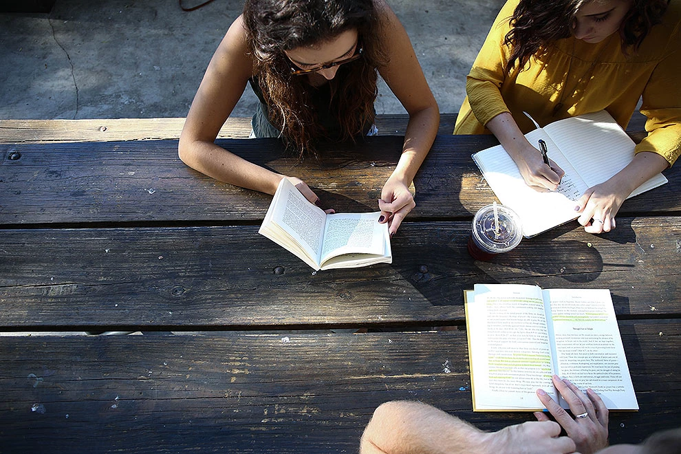 Studierende an Bank mit Büchern