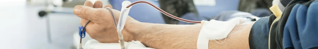 Ein Mann liegt in einem Krankenwagen mit einer Bluttransfusion im Arm.