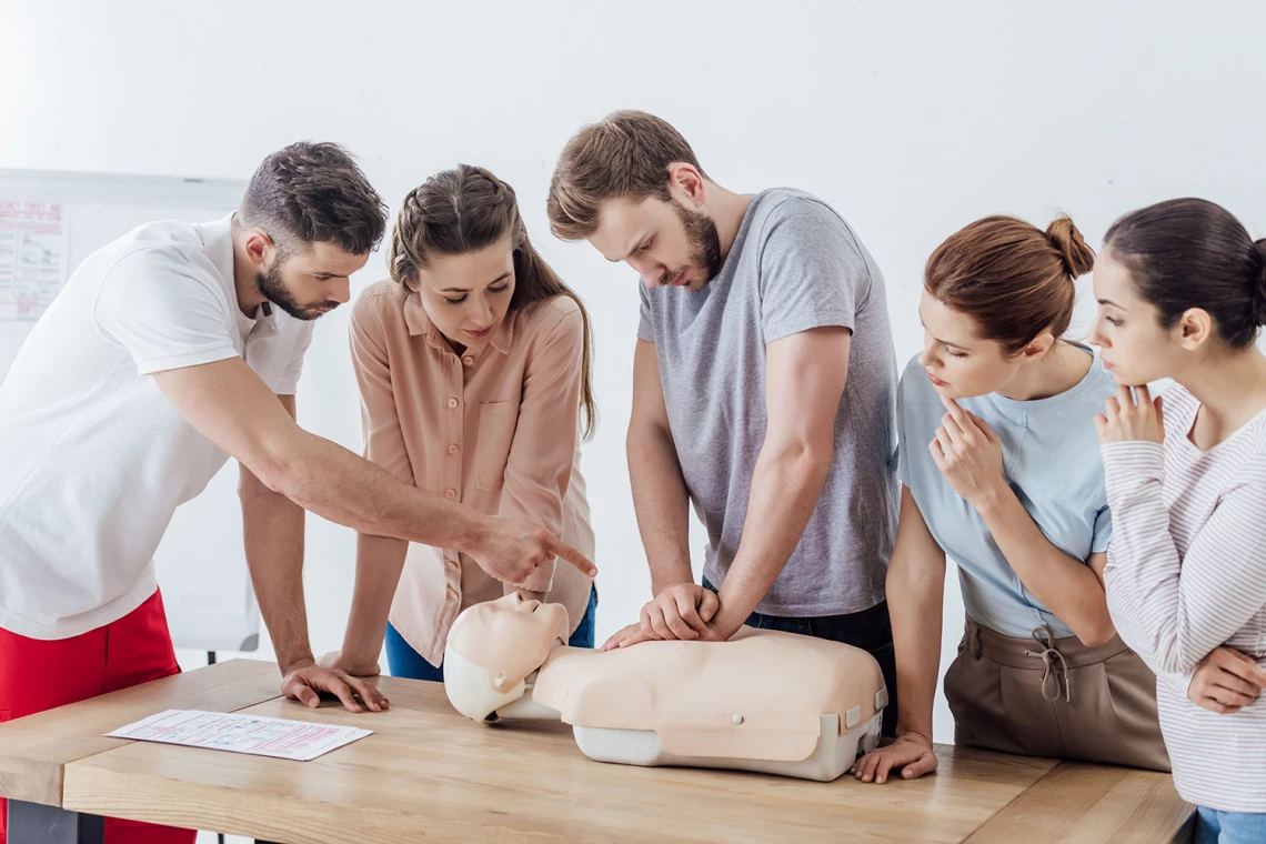 Fünf Personen probieren Herzdruckmassagen an einer Puppe aus.