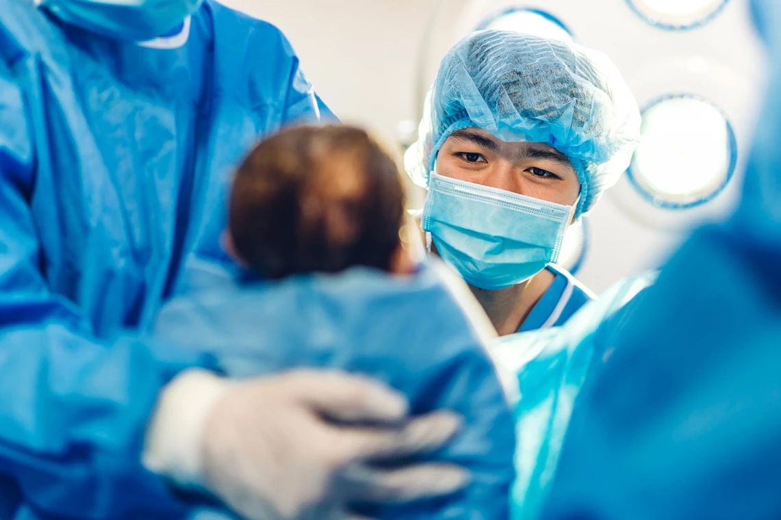Ein Neugeborenes wird von einem Arzt begutachtet.