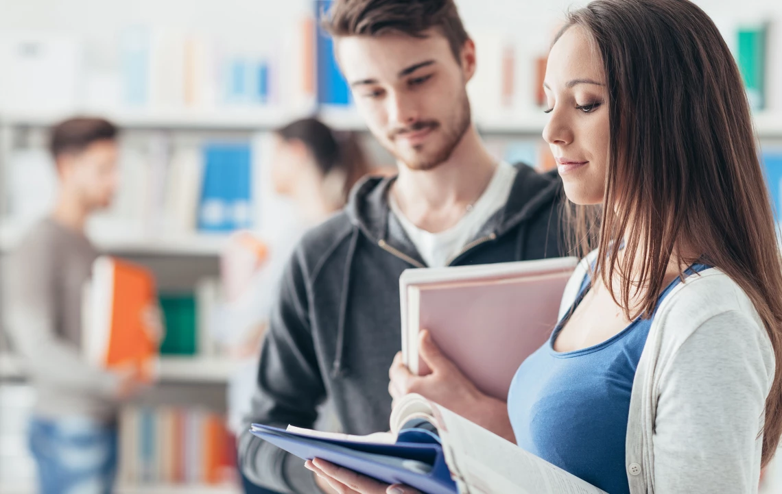 Zwei Schüler leihen sich Bücher in der Bibliothek.