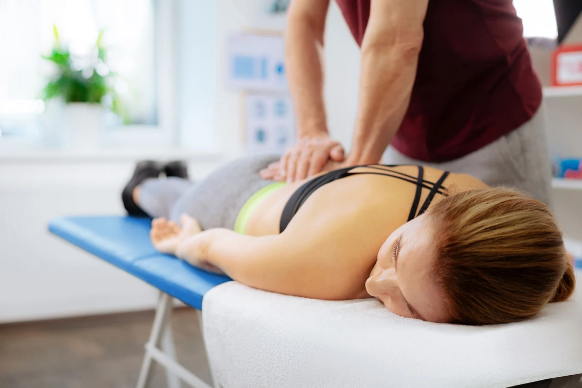 Eine Frau bekommt von einem Physiotherapeuten eine Massage.
