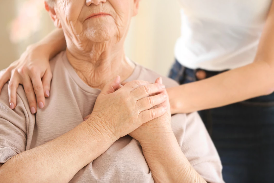 Eine junge Frau legt einer alten die Hand auf die Schulter.
