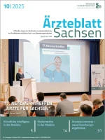 Person am Rednerpult vor Zuschauern bei laufender Bildschirmpräsentation