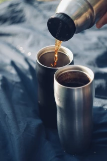Alternativtext Kaffee wird in 2 Thermos-Becher gegossen